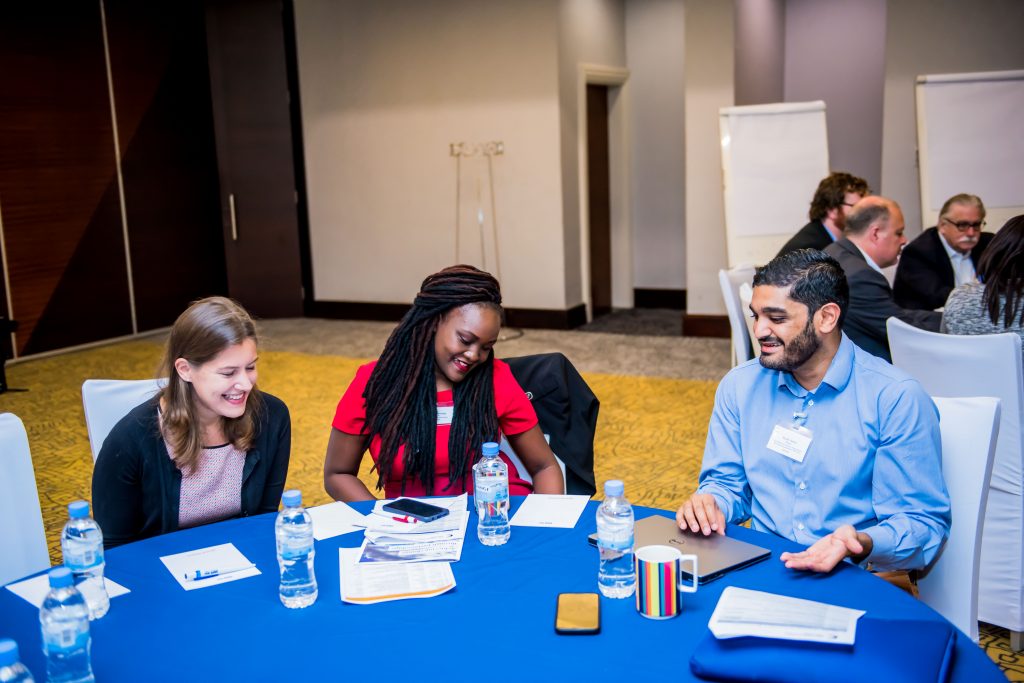 Three Oxford Policy Fellows sitting at a table in conversation.